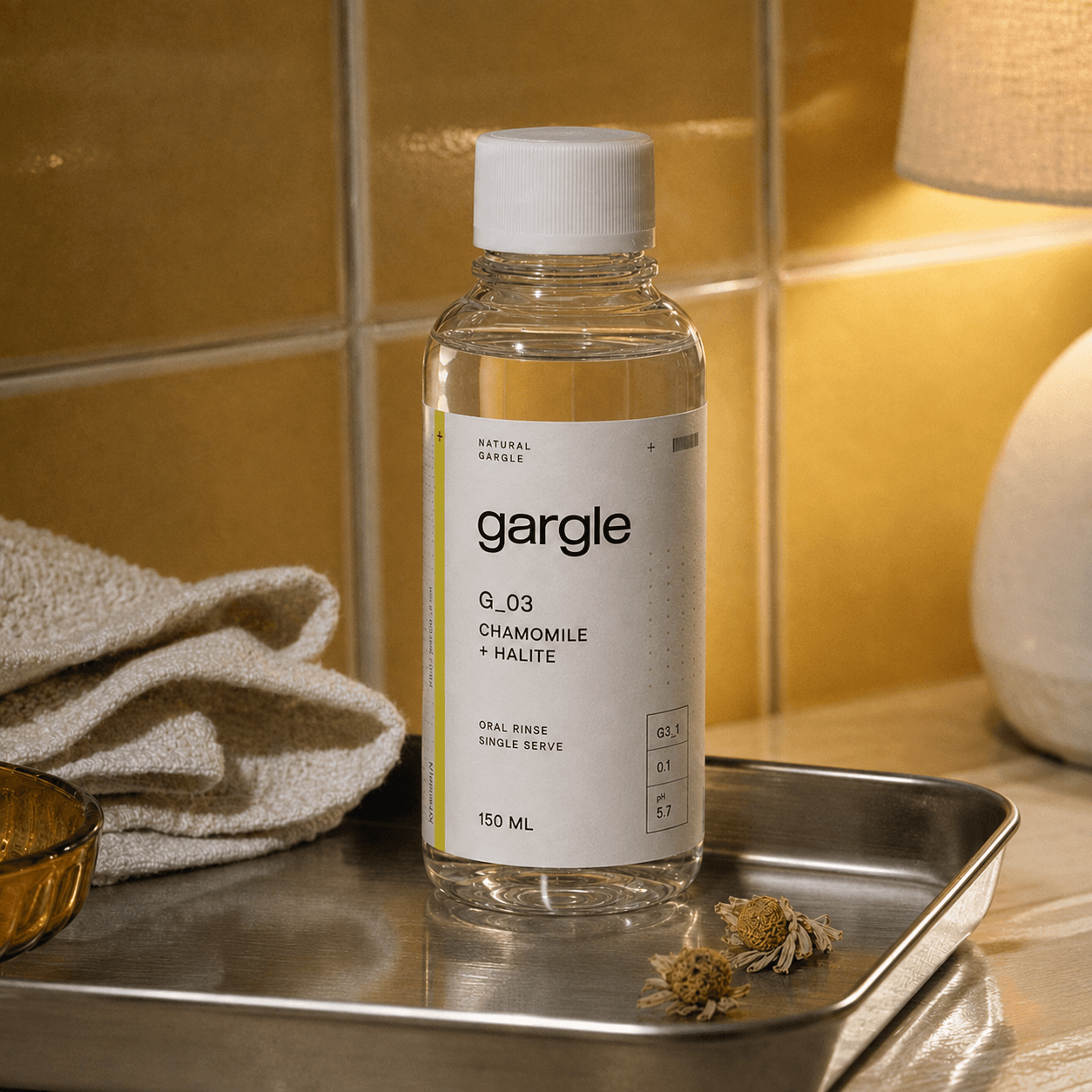 Gargle Chamomile + Halite bottle on a steel tray with dried chamomile, on a golden-tiled vanity.