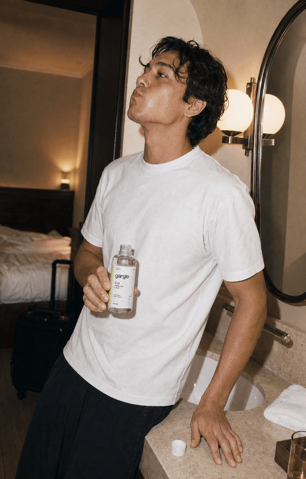 A man gargling in a hotel bathroom while travelling.